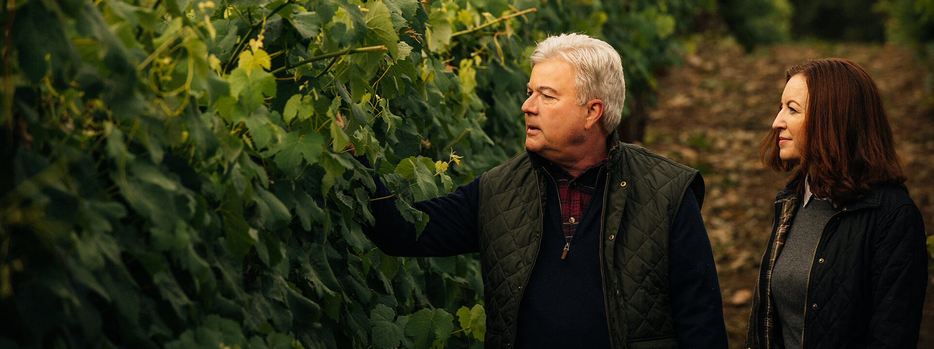 Ted and Kristy walking through a vineyard