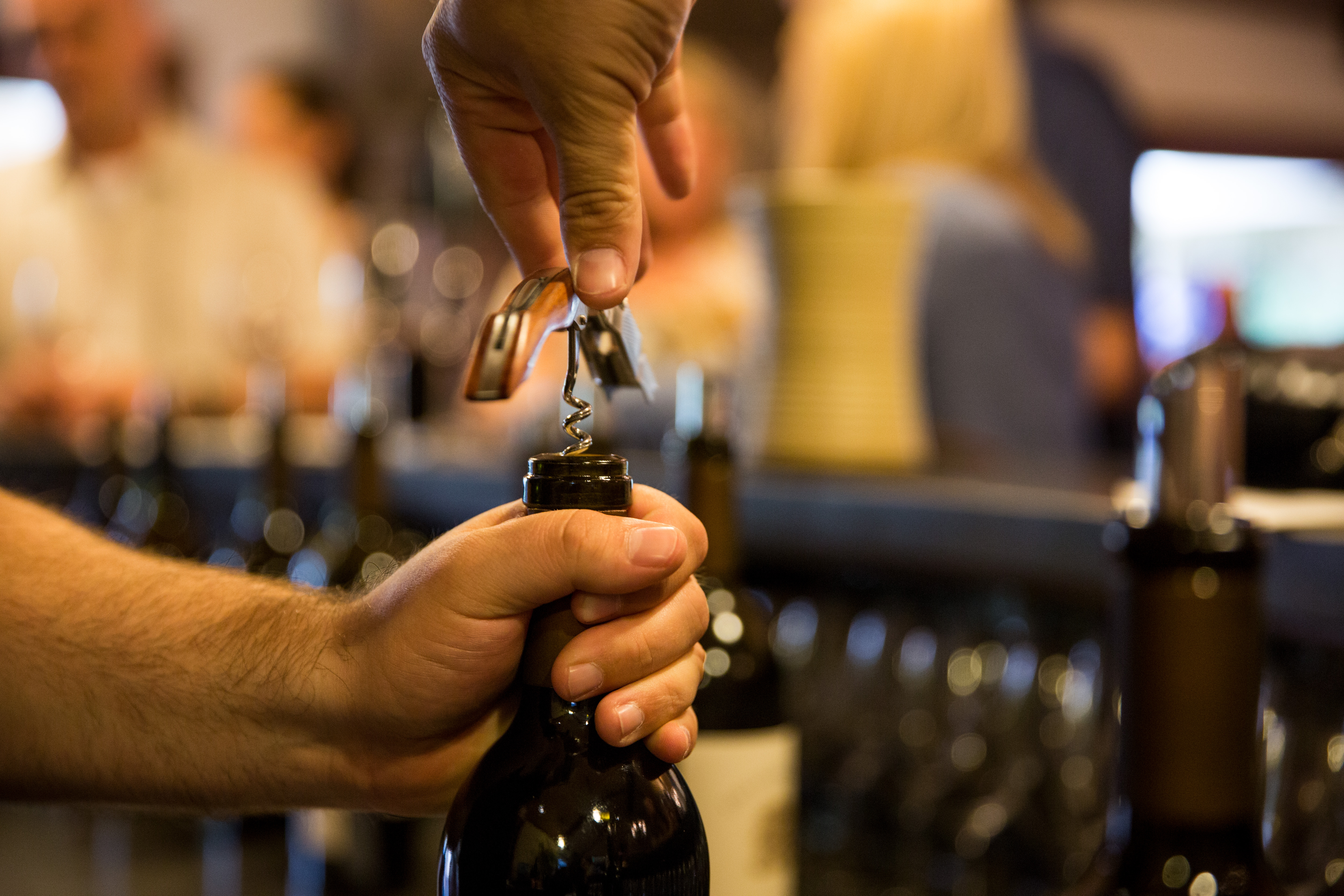 A picture of someone uncorking a bottle before a wine tasting.