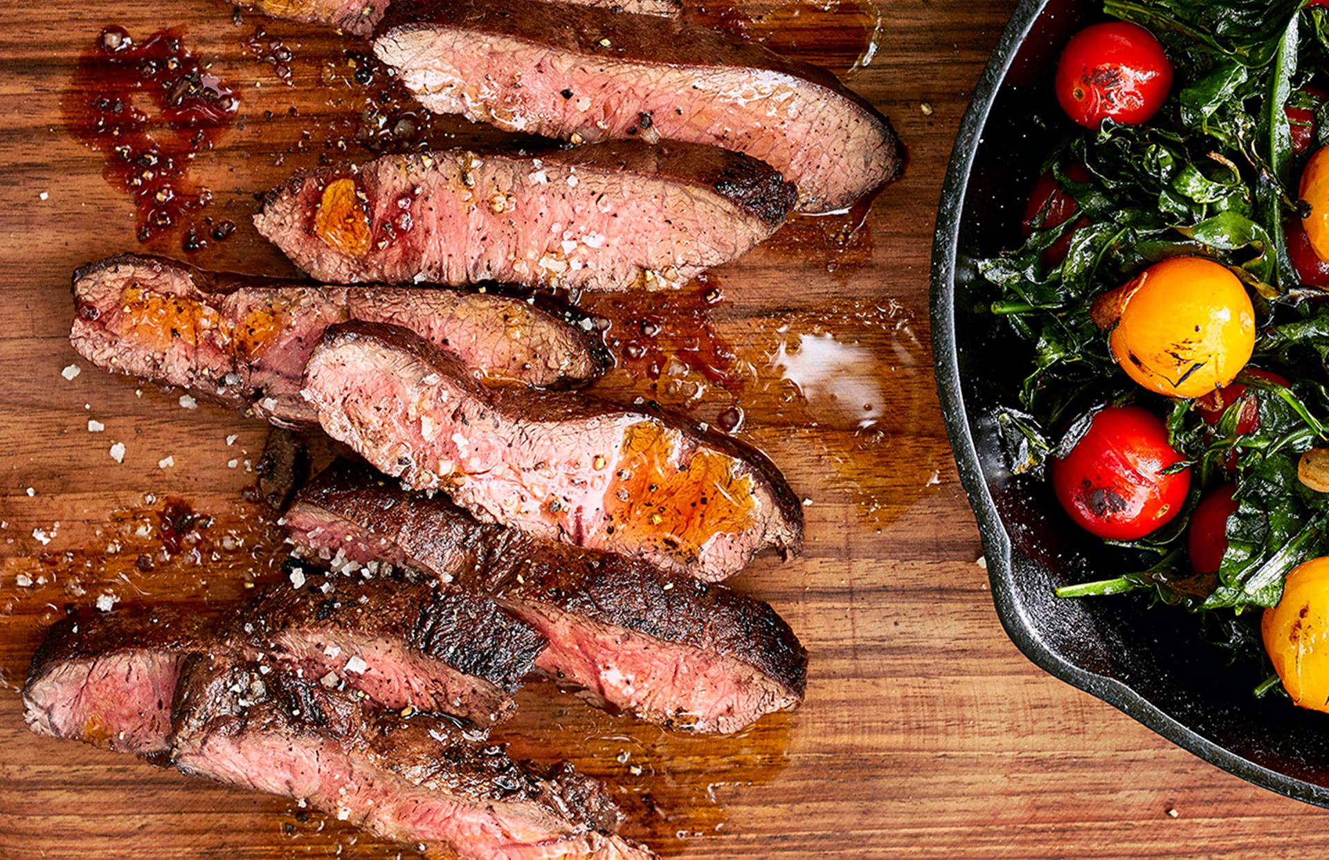 Flatiron Steak on cutting board with tomatoes